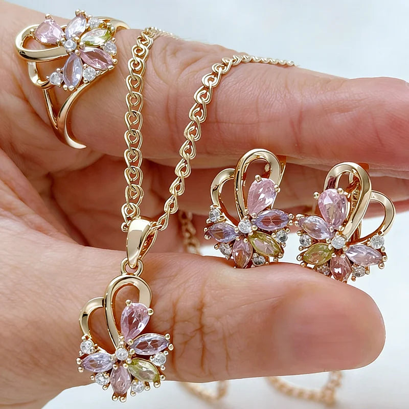 Rose gold jewelry set with pink floral crystals featuring a matching necklace, earrings, and ring in an elegant flower design.
