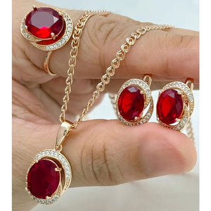 Rose gold jewelry set featuring oval ruby red crystals with matching pendant necklace, earrings, and ring in a sparkling halo-inspired design.