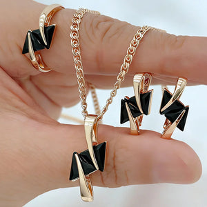 Rose gold jewelry set featuring black geometric crystals with a matching pendant necklace, earrings, and ring in a modern minimalist design.