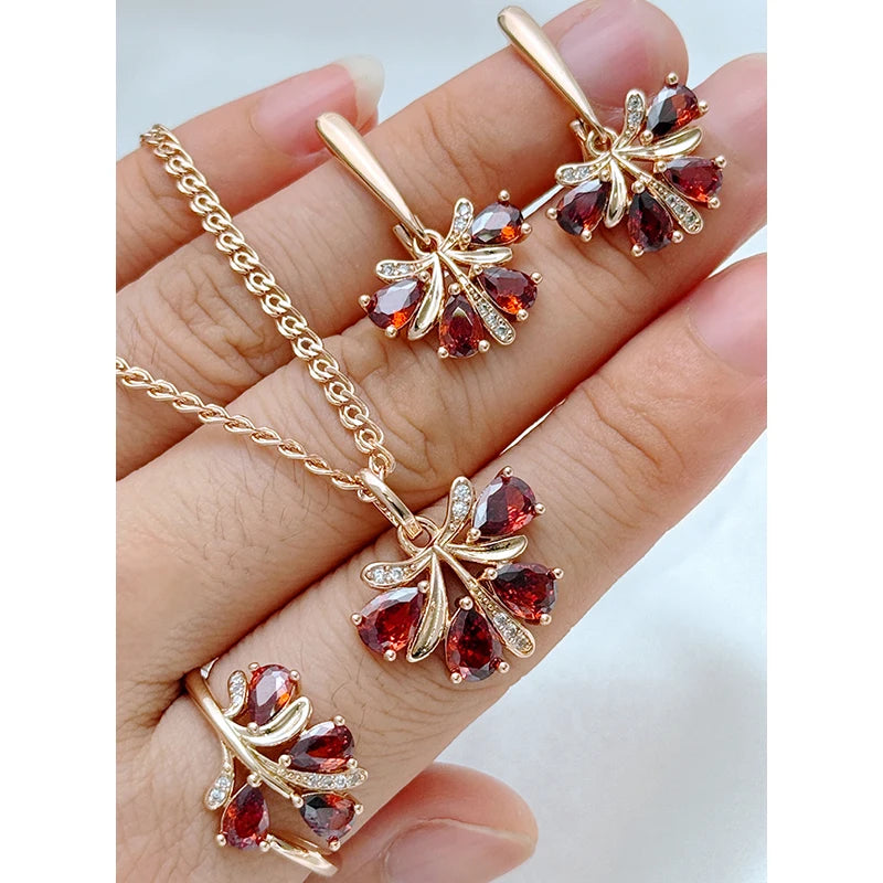 Rose gold garnet red teardrop jewelry set with matching pendant necklace, drop earrings, and ring featuring floral-inspired gemstone design.
