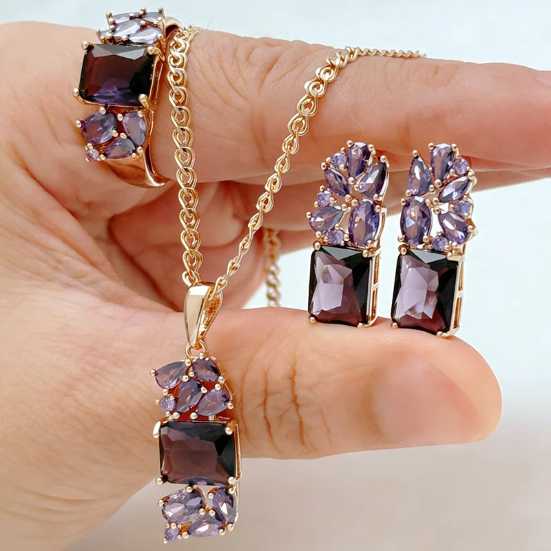 Rose gold jewelry set featuring purple crystals with a matching pendant necklace, earrings, and ring in an elegant floral-inspired design.